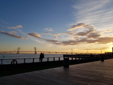 Neva üzerinde gün batımına güzel bir görünüm. Kablolu kalışlı köprüye karşı. Dolgu. korkuluküzerinde aşık bir çift oturur