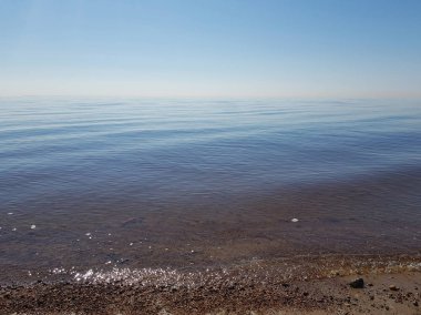 Bulutsuz güneşli bir günde fantastik renkli deniz manzarası. Mavi tonları çeşitli. Çok güzel mavi gökyüzü ve sudan yansıması