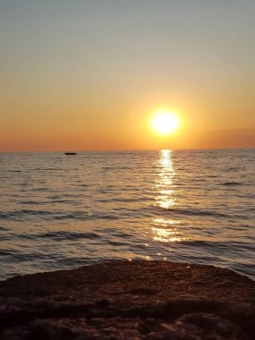 Deniz üzerinde güzel gün batımı manzarası. Sarı, mor ve kırmızı tonlarında gökyüzü, dalgalarla karanlık deniz