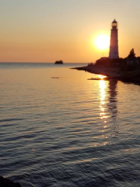 Tarkhankut deniz fenerinin, Karadeniz'in, bulutsuz bir yaz gününde batan sarı güneşin güzel manzarası. Kırım Cumhuriyeti