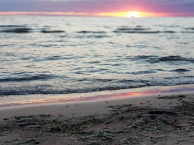 Deniz üzerinde güzel gün batımı manzarası. Sarı, mor ve kırmızı tonlarında gökyüzü, dalgalarla karanlık deniz