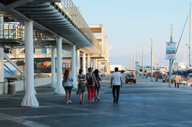 Turistler Limasol limanında yürüyor. Dört kadın ve bir erkek, v