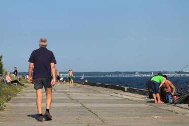 Kel kafalı, gri saçlı bir adam Pi boyunca gider.