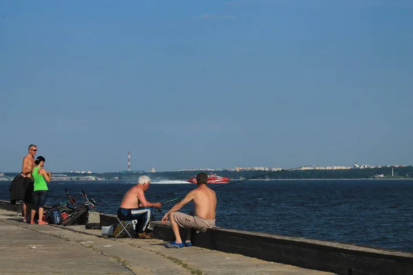 Fishermen are fishing from the pier of the Tallinn Bay. An elder — Stock Photo, Image