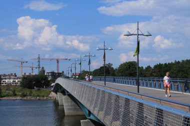 Yayalar köprüden geçer. Arka planda, inşaat 