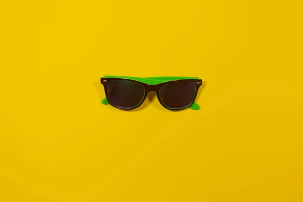 Eine Urlaubs-Sonnenbrille liegt auf einer gelben Fläche — Stockfoto
