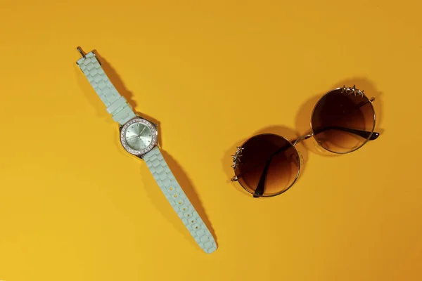 Uhr und Sonnenbrille auf gelbem Untergrund — Stockfoto