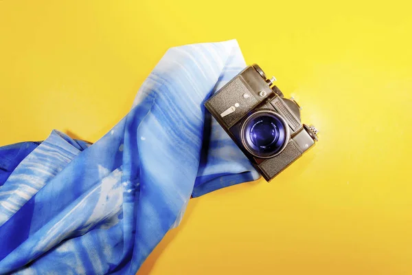 An analog camera laying on a scarf on a yellow surface Vintage camera summer concept