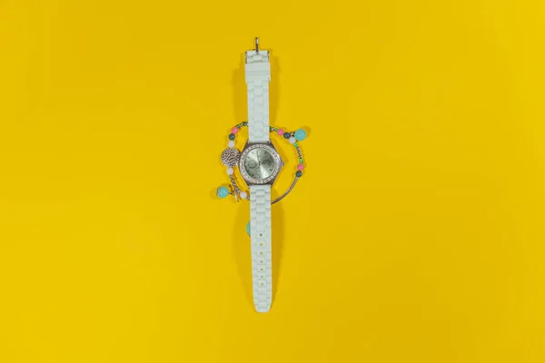 Un orologio bianco si trova al centro di un braccialetto su una superficie bianca — Foto Stock