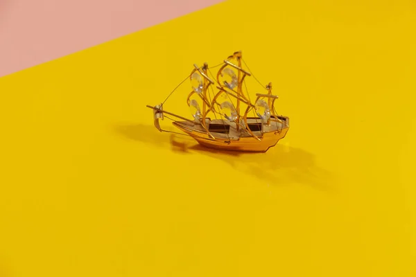Miniatur-Segelboot auf gelber und pinkfarbener Oberfläche — Stockfoto