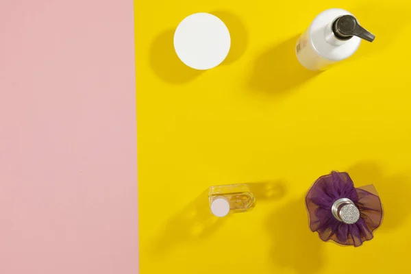 Botellas de pie sobre un concepto de verano crema de superficie rosa y amarilla — Foto de Stock