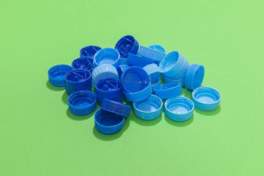 Şişe kapakları yeşil bir yüzeye uzanıyor