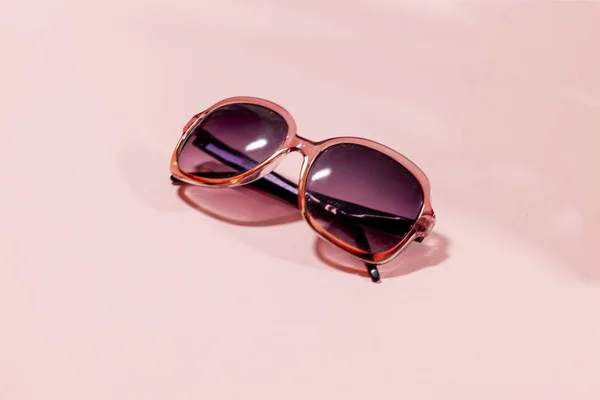 Um par de óculos de sol em uma superfície rosa — Fotografia de Stock