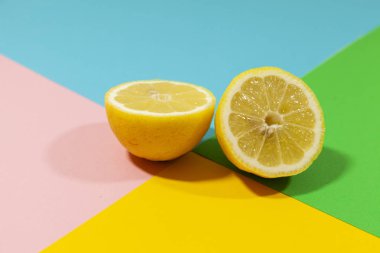 Sarı kesilmiş limon yeşil, mavi, pembe ve sarı renklerin düz bir yüzeyüzerinde yatıyor
