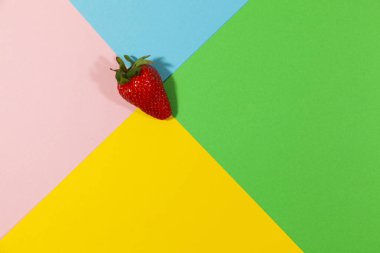 Kırmızı bütün çilek yeşil, mavi, pembe ve sarı üst görünüm taze gıda kavramı renklerde düz bir yüzey üzerinde döşeme