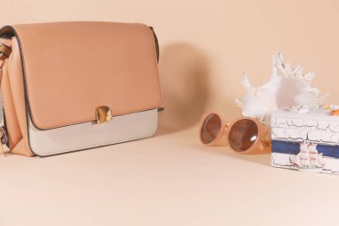Pembe ve beyaz bir çanta, güneş gözlüğü, conch ve bir kutu pembe bir yüzey üzerinde