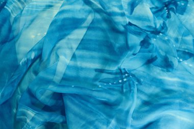 Beyaz benekli mavi bir malzeme kırışık yatıyor.