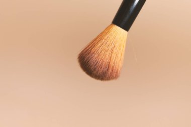 Bir makyaj fırçası pembe bir arka plan önünde resmedilmiştir