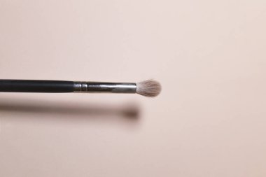 Bir makyaj fırçası pembe bir arka plan önünde resmedilmiştir