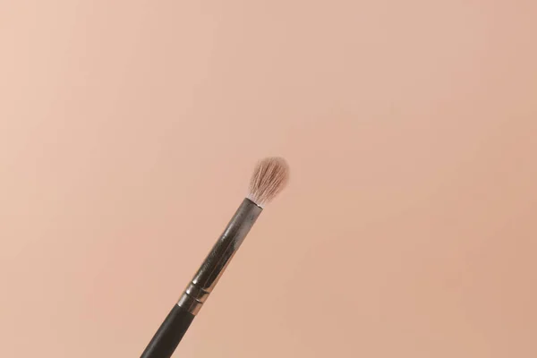 A makeup brush is pictured in front of a pink background — Stock Photo, Image