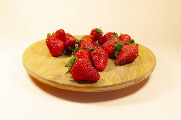 A group of red strawberries are laying on a brown turntable