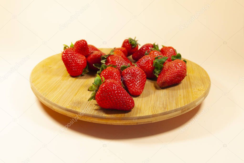 A group of red strawberries are laying on a brown turntable