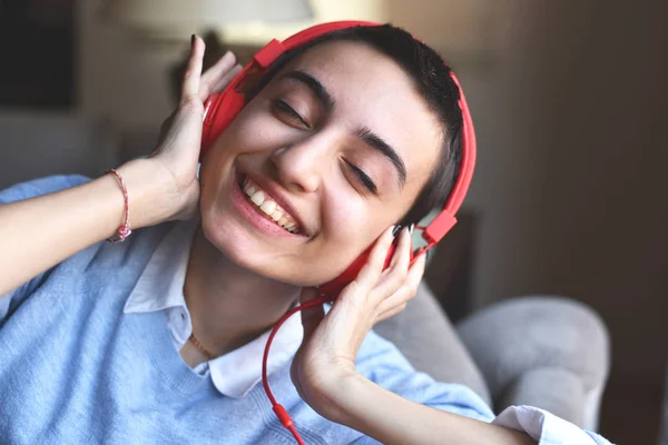 Kırmızı kulaklıklı genç bayan evde müzik dinlemeye hazırlanıyor.