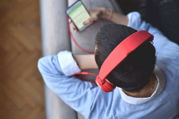 Kırmızı kulaklıklı genç bayan evde müzik dinlemeye hazırlanıyor.