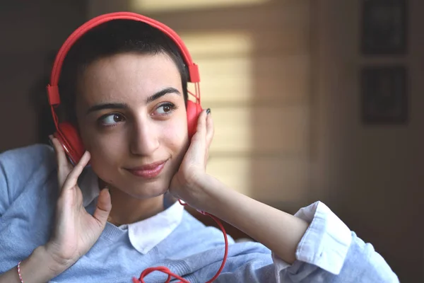 Kırmızı kulaklıklı genç bayan evde müzik dinlemeye hazırlanıyor.