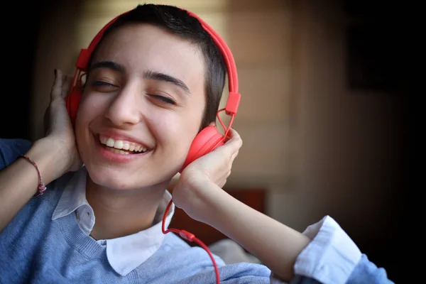 Kırmızı kulaklıklı genç bayan evde müzik dinlemeye hazırlanıyor.