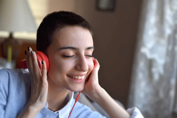 Kırmızı kulaklıklı genç bayan evde müzik dinlemeye hazırlanıyor.