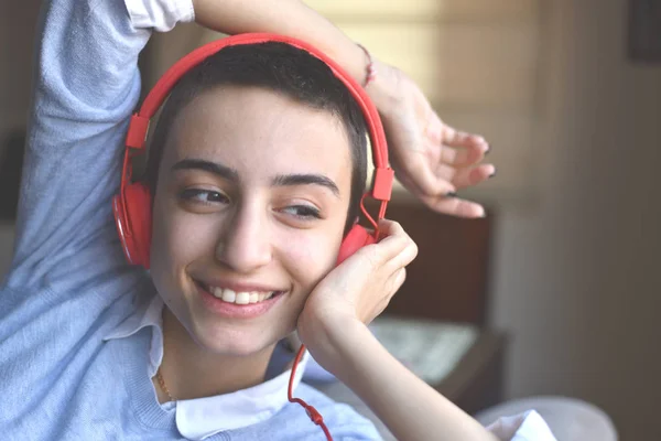 Kırmızı kulaklıklı genç bayan evde müzik dinlemeye hazırlanıyor.