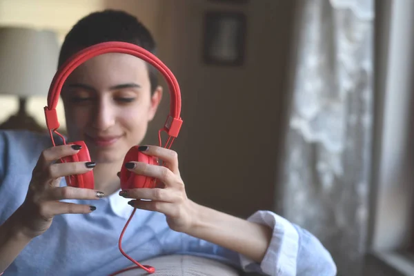 Kırmızı kulaklıklı genç bayan evde müzik dinlemeye hazırlanıyor.