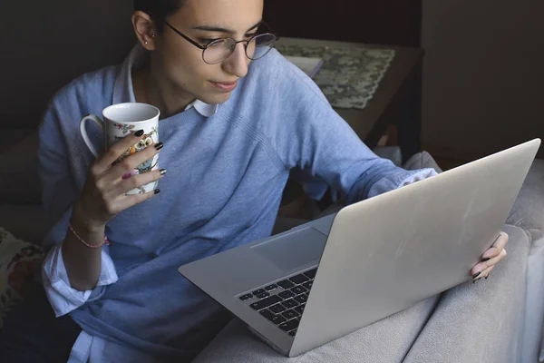 Bilgisayarlı gözlük takan ve elinde kahve olan genç bir kız.