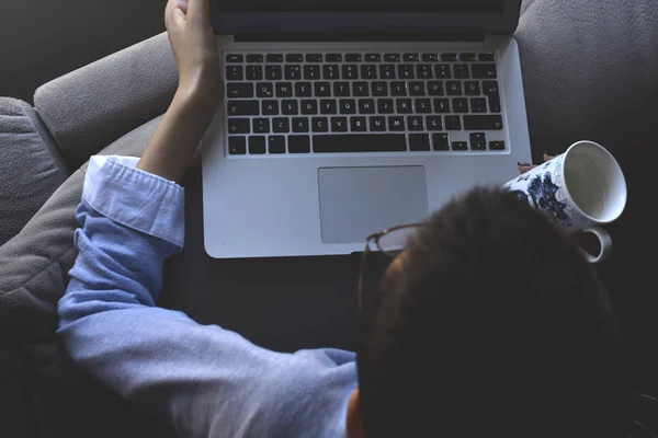 Bilgisayarlı gözlük takan ve elinde kahve olan genç bir kız.