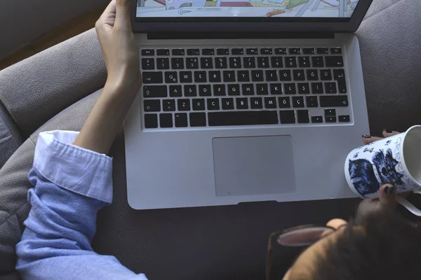 Bilgisayarlı gözlük takan ve elinde kahve olan genç bir kız.