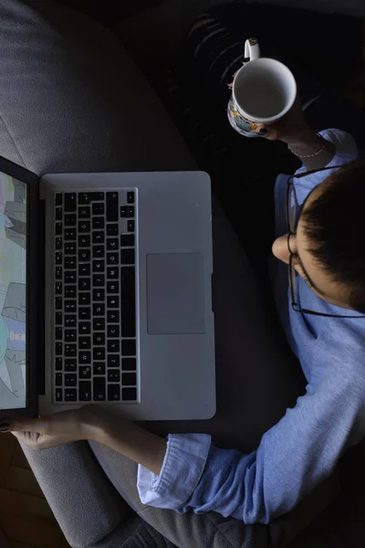 Bilgisayarlı gözlük takan ve elinde kahve olan genç bir kız.