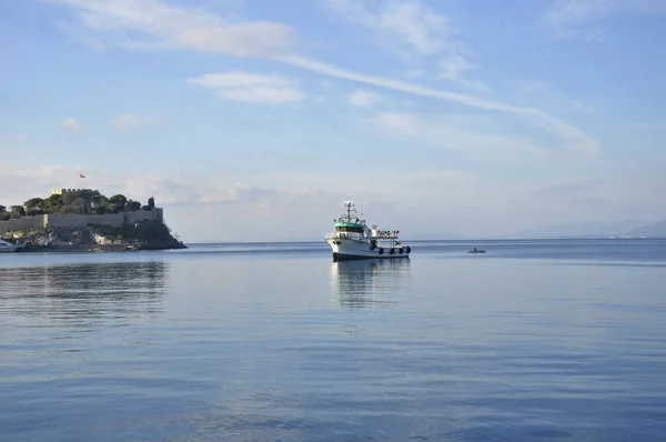 Mavi denizdeki bir teknenin altında beyaz bulutlar