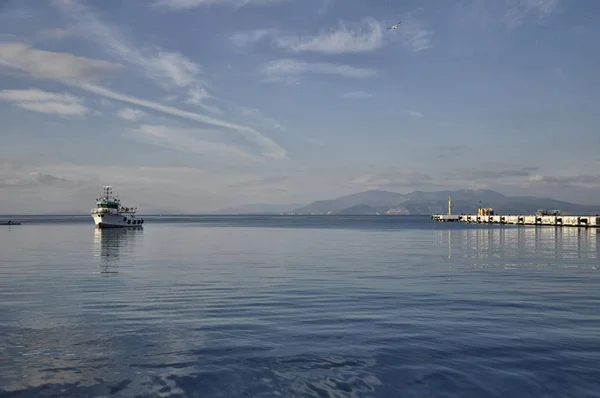 Mavi denizdeki bir teknenin altında beyaz bulutlar