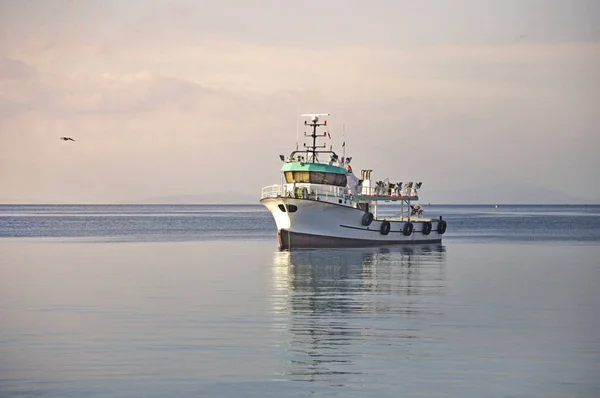 Mavi denizdeki bir teknenin altında beyaz bulutlar