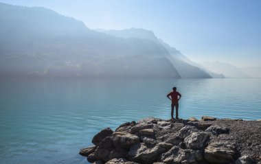 Yakın göl Brienz, İsviçre kayada duran genç bir adam. Turkuaz Gölü Brienz muhteşem dağ manzarası arasında ayarlanır.