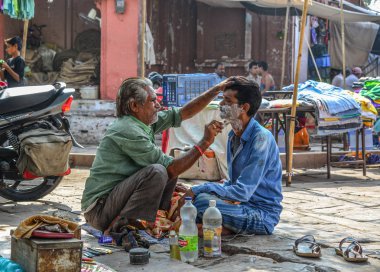 Jodhpur, Hindistan - 6 Kasım 2017. Bir adam bir tıraş Jodhpur, Hindistan bir sokak kuaför dükkanında alır. Jodhpur Rajasthan eyaletinde ikinci büyük kentidir.
