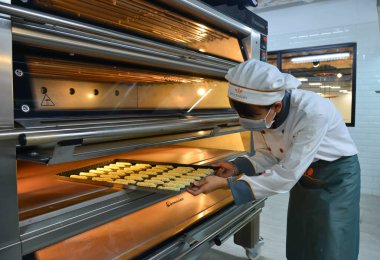 Saigon, Vietnam - 9 Ocak 2019. Kadın mutfakta, yemek koyar kek fırında