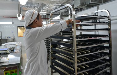 Saigon, Vietnam - 9 Ocak 2018. Taze pişmiş ekmek rafları ile Saigon (Ho Chi Minh City), Vietnam fabrikasında çalışan bir erkeğin.