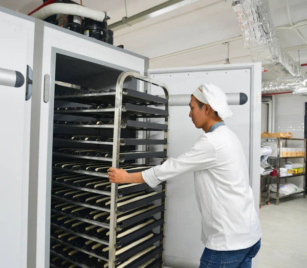 Saigon, Vietnam - 9 Ocak 2018. Taze pişmiş ekmek rafları ile Saigon (Ho Chi Minh City), Vietnam fabrikasında çalışan bir erkeğin.