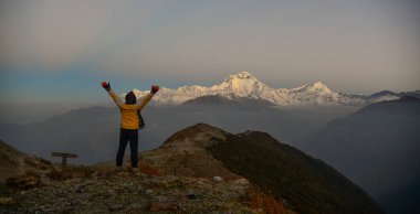 Dağ üzerinde duran ve Annapurna Massif (Nepal) doruklarına kar sunrise keyfini bir genç kadın backpacker.
