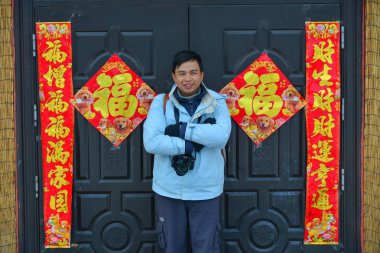 Harbin, Çin - 23 Şubat 2018. Süslemeleri için delilik yeni yıl ile kırsal evin önünde duran genç bir adam.