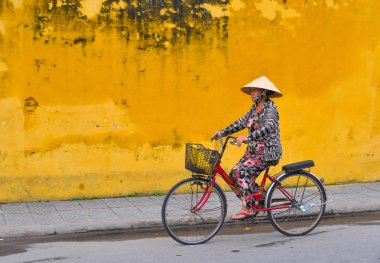 Hoi An, Vietnam - Jan 20, 2019. Hoi An eski şehir, Vietnam Caddesi üzerinde bisikleti bir yaşlı kadın. Hoi bir bir şehir, Vietnam, Güney Çin Denizi kıyısında.