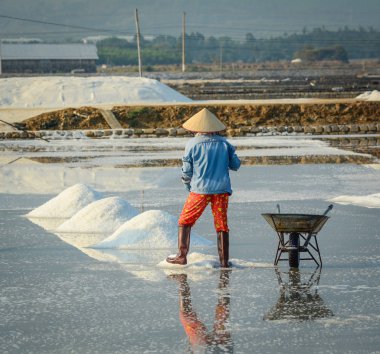 Bir çiftçi Ninh Hoa Khanh Hoa, Vietnam kasabada tuz sahasının çalışma.