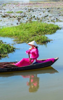 Asyalı kadın geleneksel elbise (Ao Dai) Nilüfer gölet ahşap teknede oturuyor.